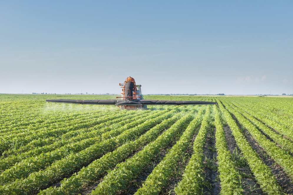 tractor spraying agrochemical in crop field 